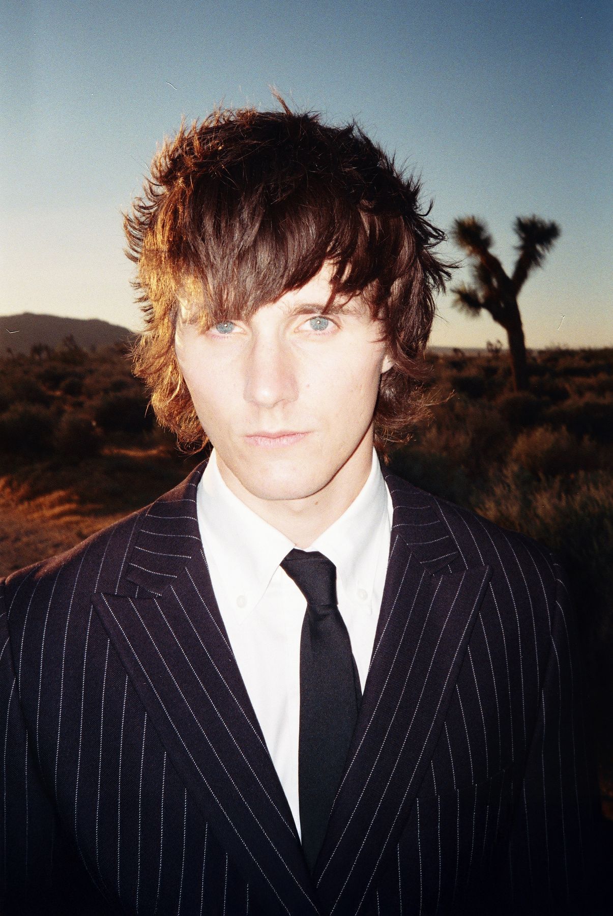 Portrait of Maybe in a pinstripe suit in the desert at golden hour